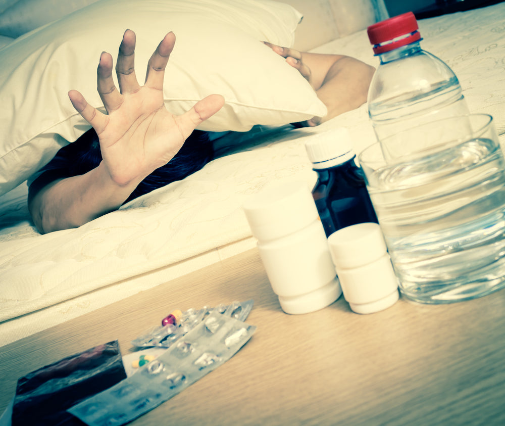 Hungover person reaching for water and medicine