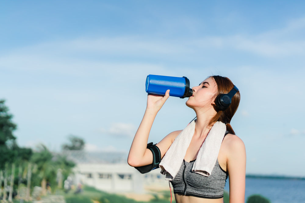 A woman drinking out of a water bottle, post workout A